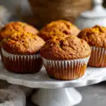 Freshly baked 2-Ingredient Pumpkin Spice Muffins on a white cake stand
